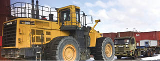 A yellow bulldozer is parked in a lot. Beskrivelse genereret af AI