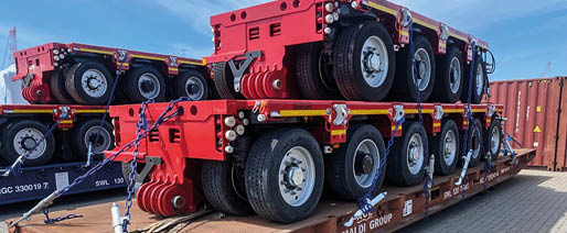 A large red truck with a flatbed trailer carrying a load of tires. Beskrivelse genereret af AI