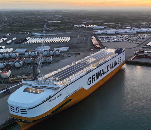 A large yellow and white ship is docked at a pier. Beskrivelse genereret af AI