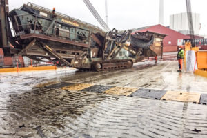 A massive road paving machine being rolled on board the ship.