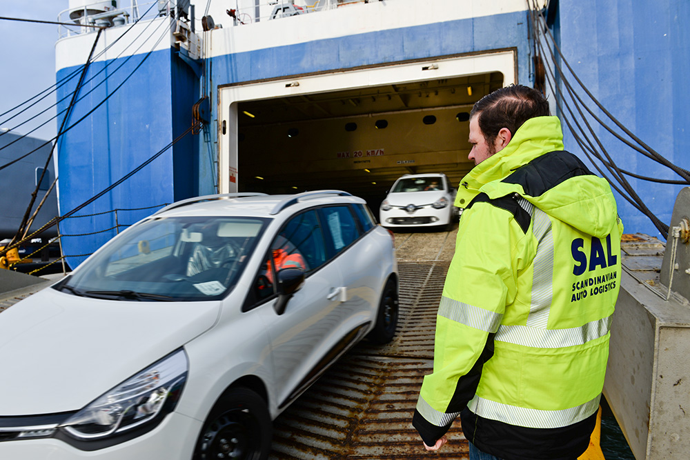 Scandinavian Auto Logistic worker overseeing the loading ramp as cars are efficiently driven down from the ship. The image highlights Multiterminal's 24/7 stevedoring service and skilled workers ensuring optimal speed, safety, and efficient cargo handling.